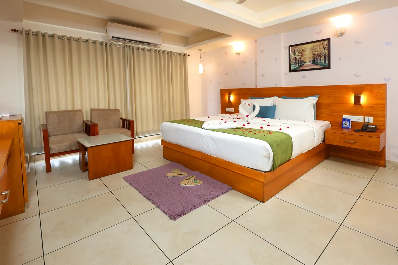 A room with a double bed, armchairs and curtained balcony doors
