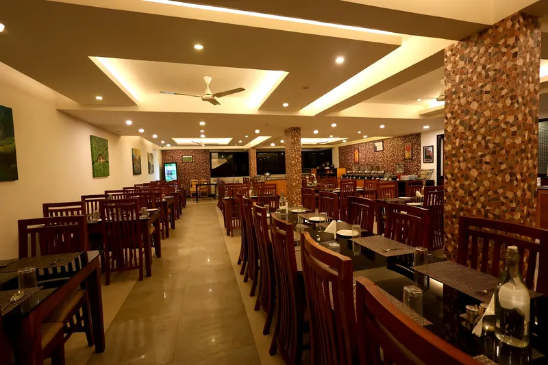 Indian Bites, the multi-cuisine restaurant: rows of wooden chairs and tables under a lit ceiling
