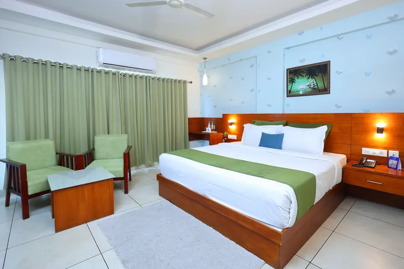 An Executive Room with a green-dressed double bed, two green armchairs and a full-width curtained window