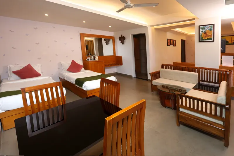 A guest room with a green-dressed bed and armchairs
